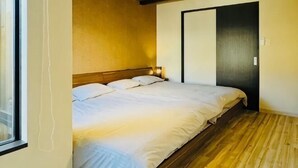 A bedroom with a bed, wooden flooring, a window, and a door. - Tachibana (Osaka)