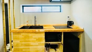 A compact kitchen with a wooden countertop, a sink, a microwave, and a stove. - Tachibana (Osaka)