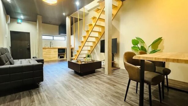 A modern interior with a staircase, a sofa, a dining table, and a kitchen area. - Tachibana (Osaka)