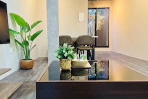 A modern reception area with a glass table, potted plants, and a seating area with chairs. - Tachibana (Osaka)