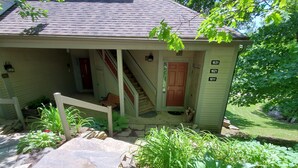 Ein eingeschossiges Haus mit einer Veranda, einer Treppe zum Eingang und einem kleinen Garten.
