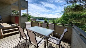 Eine Holzterrasse mit Tisch und Stühlen mit Blick auf einen See und einen Wald.