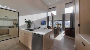A modern kitchen with a dishwasher, a large island, and a dining area with a view. - Downtown Nashville Penthouse|Huge Skyline Balcony (Nashville)