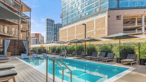 A rooftop pool with lounge chairs and umbrellas, surrounded by high-rise buildings. - Downtown Nashville Penthouse|Huge Skyline Balcony (Nashville)