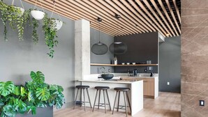 Une cuisine moderne dotée d’un îlot central, de tabourets de bar, de plantes suspendues et de luminaires suspendus.
