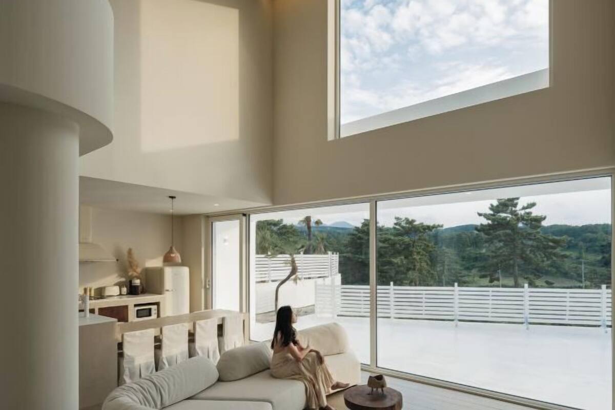 Un interior moderno con un ventanal grande, un sofá y una zona de comedor.
