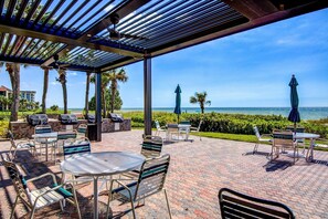 Une terrasse extérieure avec des tables et des chaises, un espace abrité et une vue sur l’océan.