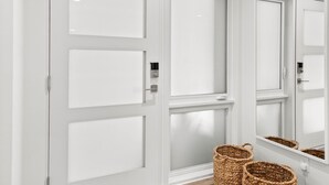 Un couloir avec des portes blanches, un plancher en bois et deux paniers en osier.