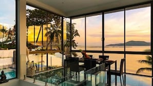 A modern room with a glass balustrade overlooking a beach and sunset. - Bella Samui Beach Villa (Koh Samui)