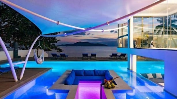 A modern pool area with a view of the sea, lounge chairs, and a hanging chair. - Bella Samui Beach Villa (Koh Samui)