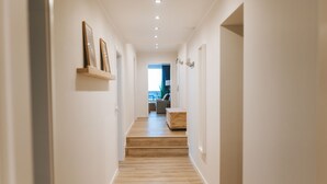 A hallway with wooden flooring, white walls, and a view into a living area with a sofa and a coffee table. - Vacation apartment Schneeglück for 10 people with large terrace (Winterberg)