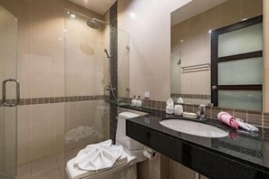 A modern bathroom with a glass shower enclosure, a black countertop sink, and a large mirror with a frosted glass panel. - Trixie Town House Unit 2 (Phuket)