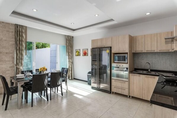 A modern kitchen with a dining area, a refrigerator, a microwave, and a sink. - Trixie Town House Unit 2 (Phuket)