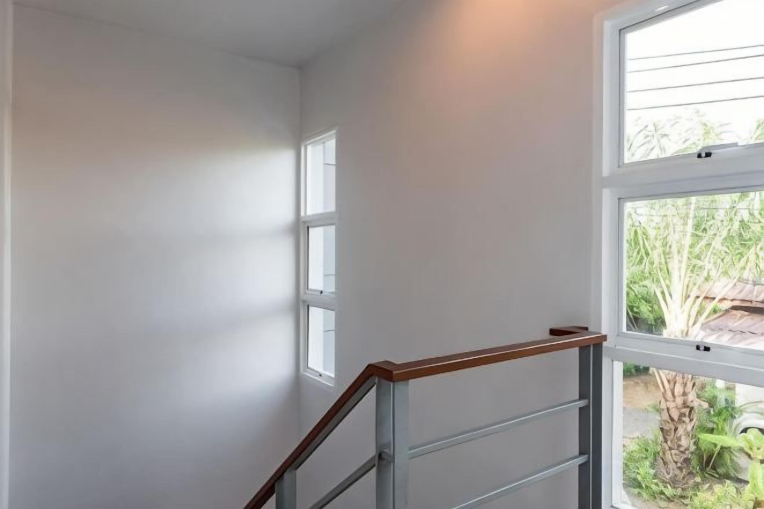 Eine Treppe mit einem hölzernen Geländer, das zu einer Zwischenebene führt.