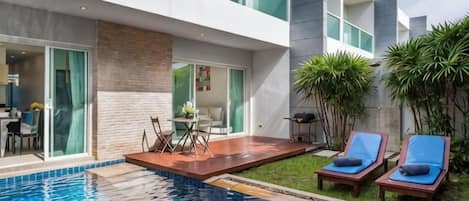 A modern hotel with a swimming pool, outdoor seating, and a well-maintained garden.