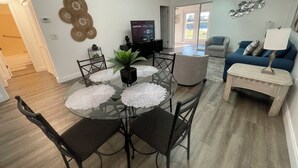 A dining area with a glass table, black chairs, and a potted plant.