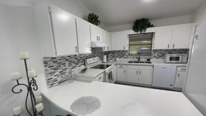 A modern kitchen with white cabinets, a microwave, and a sink.