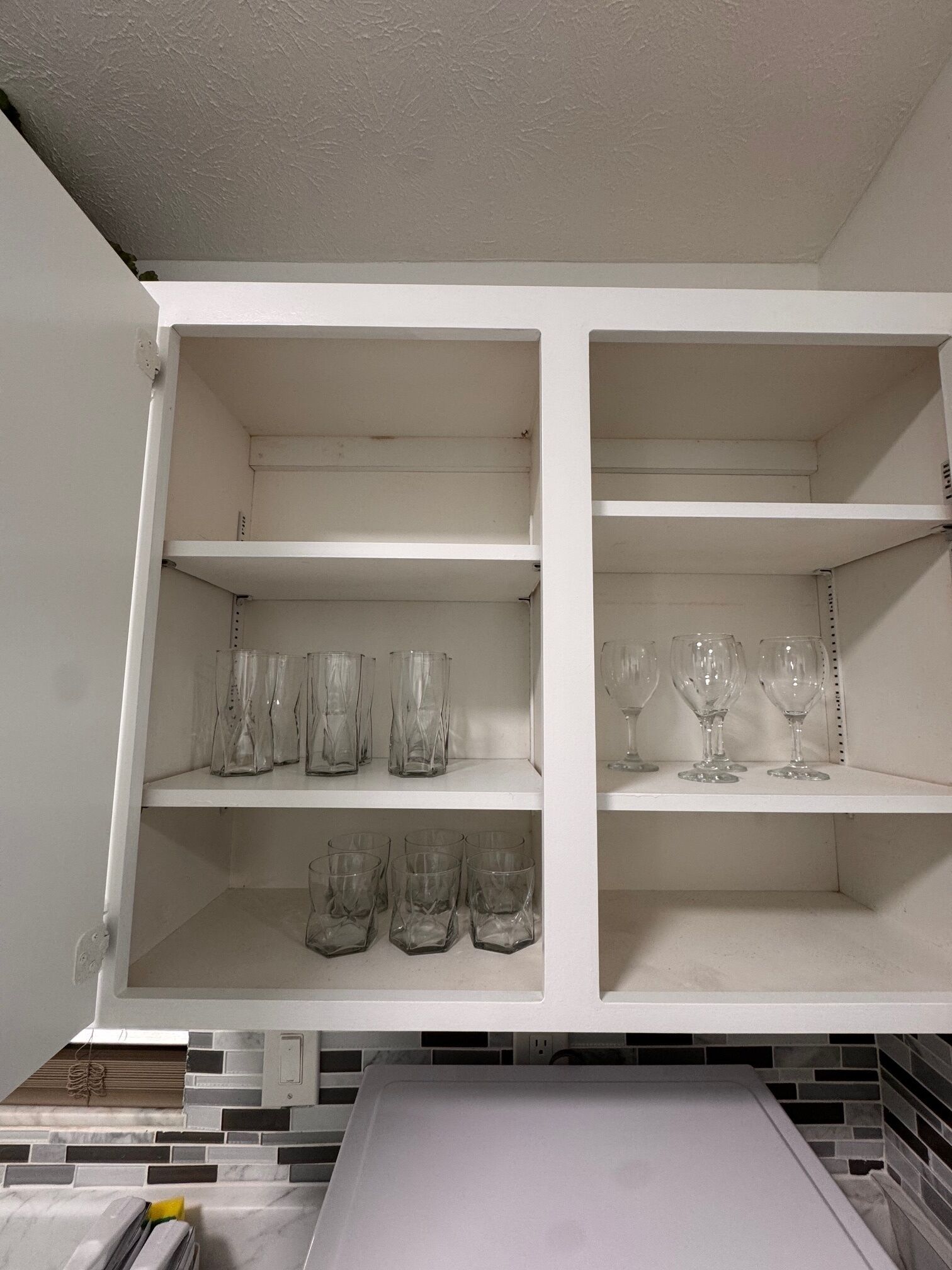 Un estante blanco con varios objetos de vidrio.