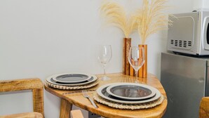 Une table à manger dressée avec des assiettes, des couverts et deux verres à vin, agrémentée de vases décoratifs contenant des plumes d’herbe de la pampa.