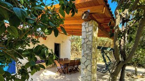 A covered outdoor dining area with a stone pillar, a hammock, and a wooden table and chairs. - [Casa dolce sole]  Holiday Home in Sciacca - Comfort and Relax Near the Sea! (SCIACCA)