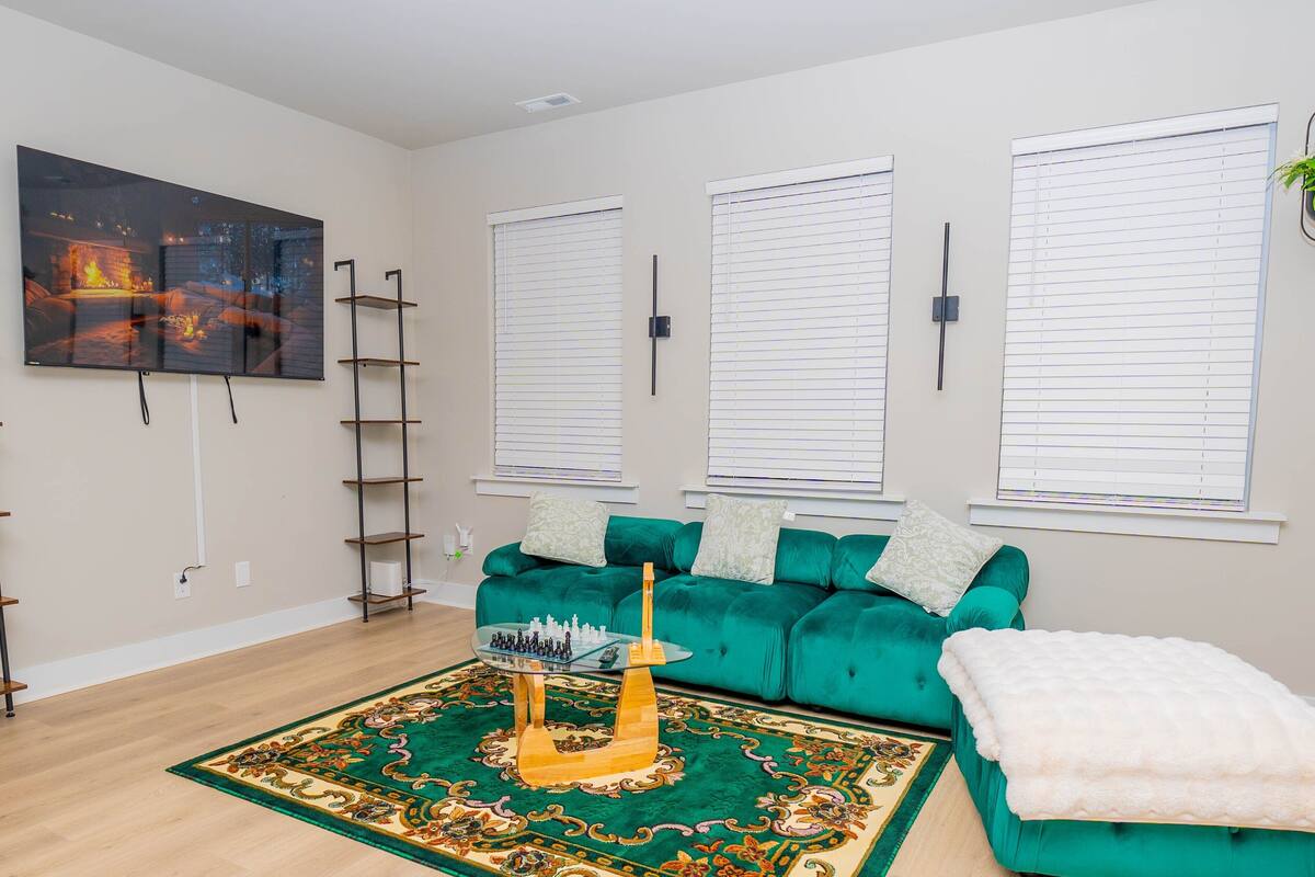 Una sala de estar con un sofá verde, un televisor grande y una mesa de centro decorativa.
