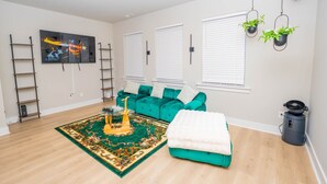 Un salon moderne avec un canapé de couleur turquoise, un tapis décoratif, un téléviseur fixé au mur et un ventilateur de plafond.