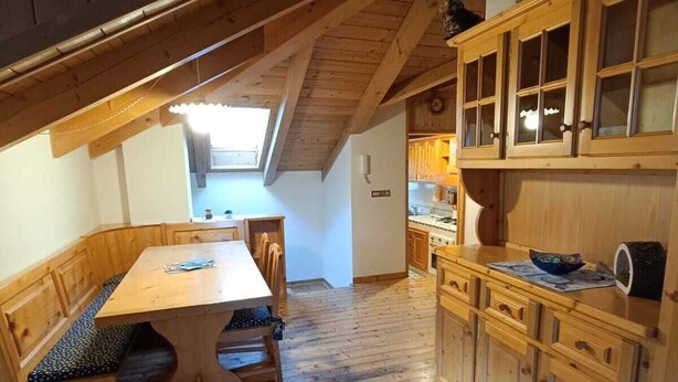 Een houten interieur met een eethoek, keuken en een schuine plafond.