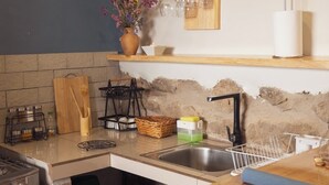 A kitchen with a wooden countertop, a sink, and a stove. There is a vase with flowers on the countertop and a shelf with wine glasses above the sink. - Dona Catta Boutique Loft—Just 10 minutes from the station! (Ollantaytambo)