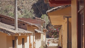 A narrow cobblestone street flanked by traditional buildings with balconies, set against a mountainous backdrop. - Dona Catta Boutique Loft—Just 10 minutes from the station! (Ollantaytambo)