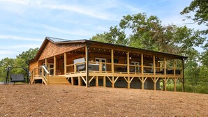 Een houten vakantiehuis met een overdekte veranda en een schommel.'