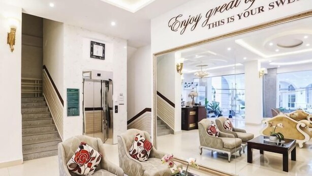 Eine moderne Lobby mit einer Treppe, einem Empfangstresen und einem großen Spiegel, der das Innere widerspiegelt.