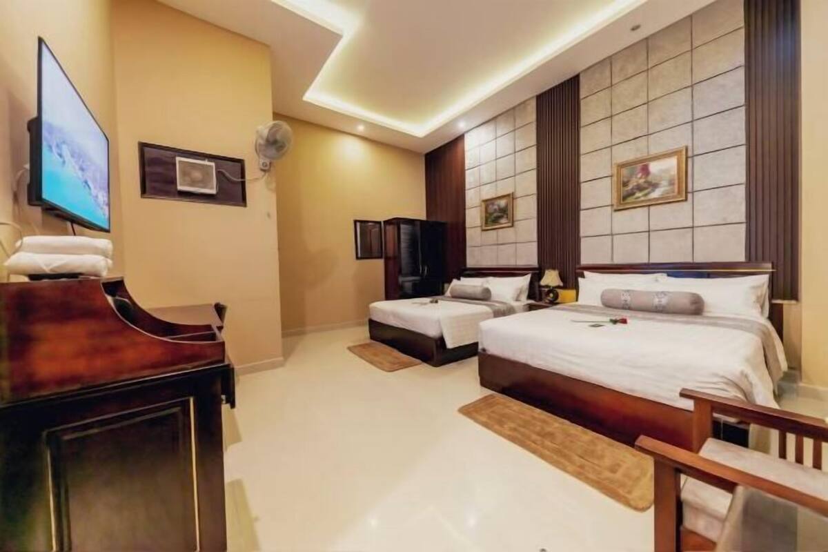 A hotel room with two beds, a TV, a desk, and a chair.