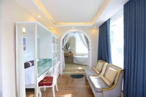 Una habitación con un escritorio de vidrio, un sofá y vistas al baño.