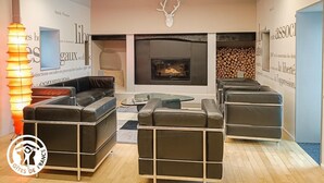 A modern living room with leather sofas, a glass coffee table, and a fireplace. - Gîtes de France® - Paty (CAJARC)