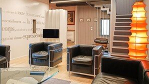 A modern living room with leather sofas, a glass coffee table, and a unique orange pendant light. - Gîtes de France® - Paty (CAJARC)