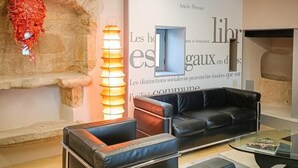 A modern living room with a stone fireplace, leather sofas, and a glass coffee table. - Gîtes de France® - Paty (CAJARC)
