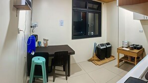 A compact kitchen with a dining area, a window, and a small table with a stool. - RedDoorz near Baguio Night Market (Baguio)
