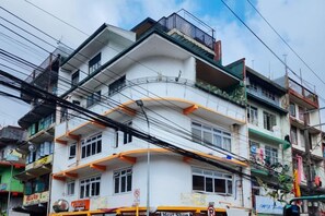 Un edificio de varios pisos con balcones, una carnicería y señalización visible.
