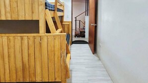 A wooden bunk bed with a ladder, a staircase, and a door leading to another room. - RedDoorz near Baguio Night Market (Baguio)