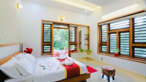 A hotel room with a bed, a small table, a chair, and a window with blinds.