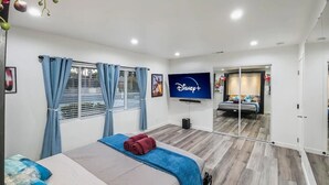 Ein Hotelzimmer mit Bett, Fernseher, Spiegel und einem fenster mit Vorhängen.