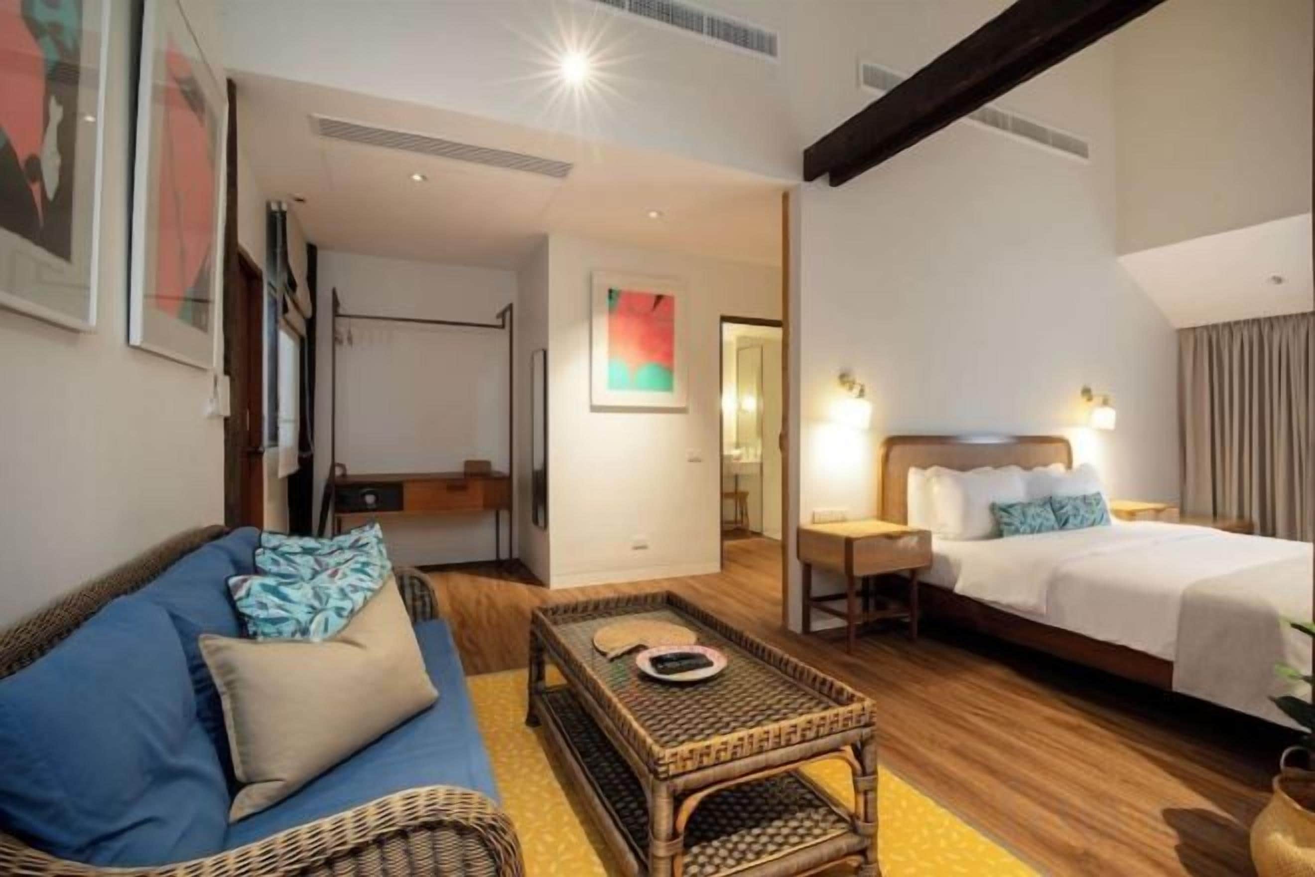 Habitació d'hotel amb un llit, un sofà, una taula petita i un mirall.