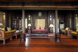 Een klassieke kamer met een houten vloer, een zitgedeelte met een bank in het midden en een decor kast.
