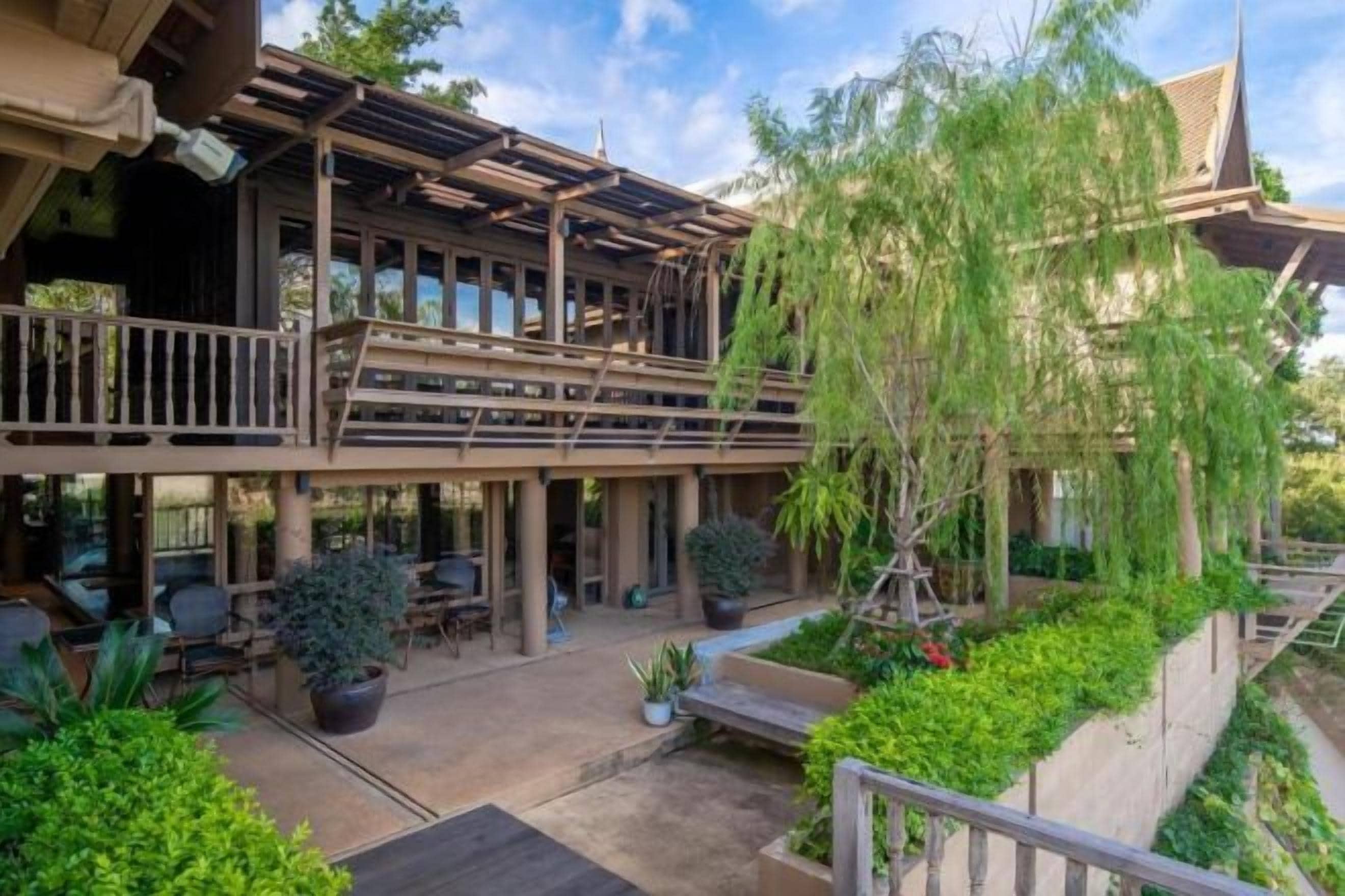 A two-story building with a balcony, outdoor seating area, and potted plants.