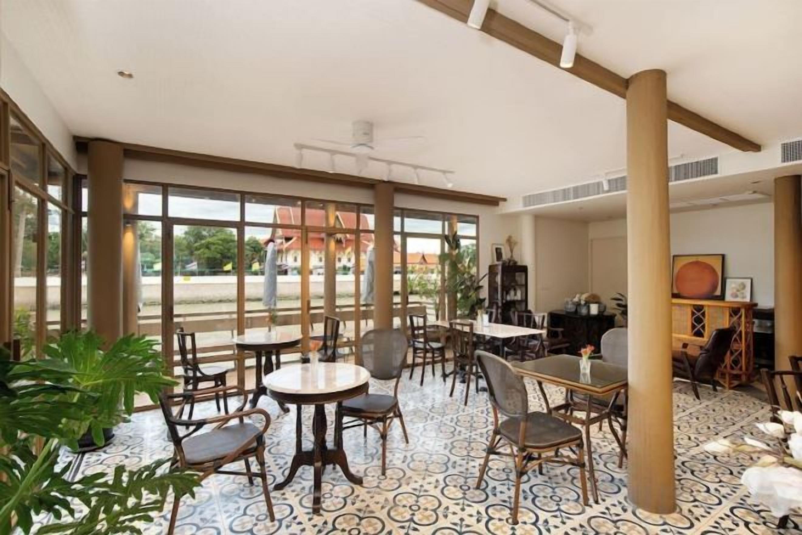 A spacious indoor area with multiple tables and chairs, large windows, and a patterned floor.