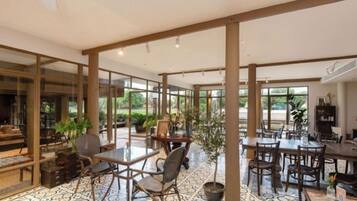 Un espacio interior amplio con varias mesas y sillas, ventanas grandes y un suelo con diseño.