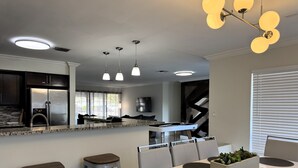 Une cuisine moderne dotée d’un îlot central intégré, d’appareils électroménagers en acier inoxydable et de luminaires suspendus.