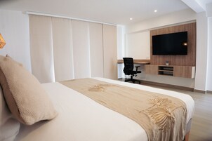 A modern hotel room with a large bed, a desk, and a TV mounted on the wall.