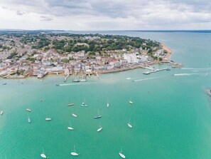 An aerial view of a coastal town with a marina, buildings, and boats.