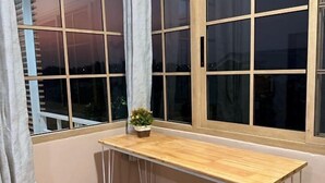 A room with a window, a wooden table, two stools, and a potted plant. - Saengcanthr (Nakhon Ratchasima)